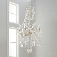 a chandelier hanging from the ceiling in a room with white walls and windows