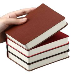 a hand holding two books on top of each other in front of a white background