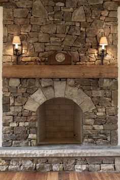 a stone fireplace with two lamps on each side and a clock above the fire place