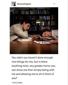 a man and woman laying on top of a wooden table next to a book shelf