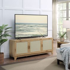 a flat screen tv sitting on top of a wooden cabinet in front of a window