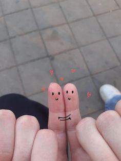 two fingers with faces drawn on them are in the middle of each other's fingers