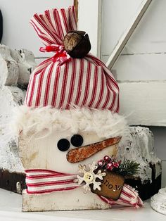 a snowman made out of wood with a red and white striped hat on top