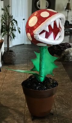 a fake mushroom is sitting in a potted plant with its mouth open and it's tongue out