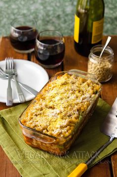 a casserole dish on a table with wine and silverware