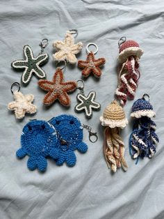 crocheted keychains and hats are arranged on a bed with white sheets