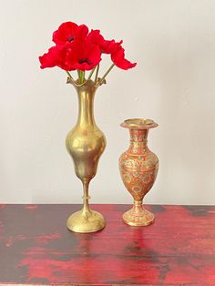 two gold vases with red flowers in them