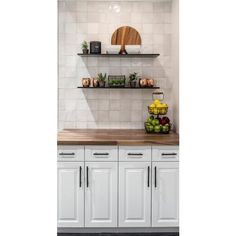 a kitchen with white cabinets and shelves filled with fruit on top of it's counter tops