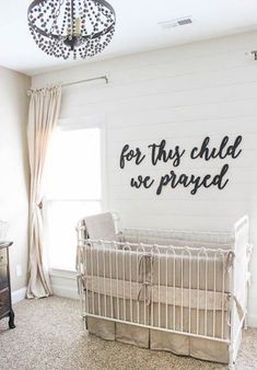 a baby crib in the corner of a room with a chandelier above it