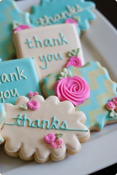 decorated cookies on a plate with thank you written on the ones in blue and pink