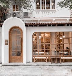 the outside of a restaurant with wooden tables and chairs