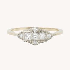 an antique diamond and gold ring, with three stones in the center on a white background