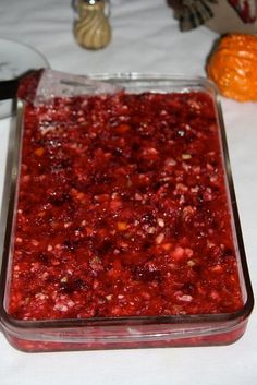 a glass dish filled with cranberry sauce on top of a table