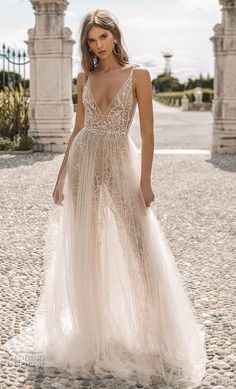 a woman in a wedding dress standing on a cobblestone road with an archway behind her