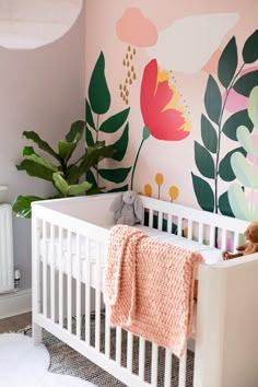 a baby's room decorated in pink, green and yellow with flowers on the wall