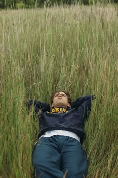 a boy laying in the grass with his eyes closed