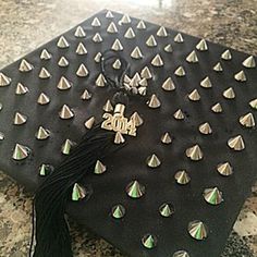 a black graduation cap with gold studs and tassels on it sitting on a marble surface