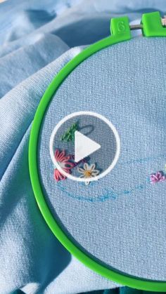 an embroidery project is being displayed on a piece of blue fabric with flowers and leaves