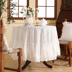 a table with two chairs and a vase filled with white flowers on top of it