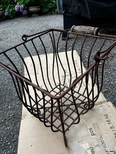 a metal basket sitting on top of a piece of cardboard next to a planter