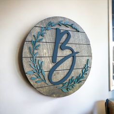 a wooden sign with the letter j on it hanging on a wall next to a chair