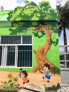 a mural on the side of a building depicting children playing in front of a tree