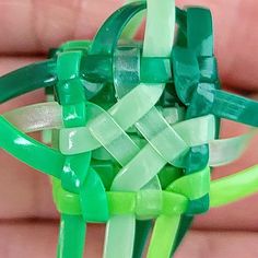 a close up of a green and white object in someone's hand with it's fingers