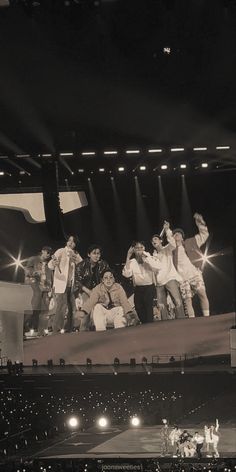 a group of people standing on top of a stage in front of an audience at a concert