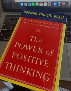 the power of positive thinking by norman vincent peale on a laptop computer with a red book cover