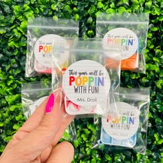 someone holding up four small plastic bags with different colored candies in them and the words popin'with fun written on them