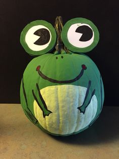 a green frog pumpkin sitting on top of a table