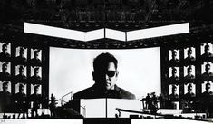 a black and white photo of a man in front of a large screen with people on it