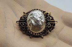 This is a beautiful, vintage piece of jewelry from an American jewelry designer. A small, prong-set baroque pearl is nestled in a filigree designed oval brooch by Sandor, with small leaves surrounding. The gold tone open design metal brooch is antiqued. The brooch measures 1 3/8 inches across by 1 inch tall. It's three-dimensional design creates a 3/8 inch depth. According to several websites, Sandor Goldberger founded the Sandor brand in 1938. Characteristic of his decorations - pastel flowers Elegant Baroque Wedding Brooches, Elegant Baroque Brooches For Formal Occasions, Ornate Baroque Brooch For Formal Occasions, Victorian Baroque Brooch For Formal Occasions, Ornate Baroque Brooches For Formal Occasions, Victorian Baroque Brooches For Formal Occasions, Vintage Baroque Brooch Jewelry, Elegant Gold Baroque Brooch, Elegant Gold Baroque Brooches