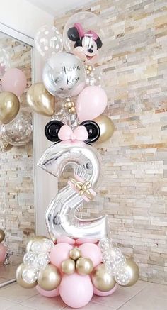 a balloon arch with minnie mouse balloons on it in front of a mirror and wall