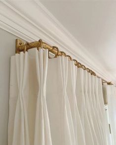 the curtain is hanging on the wall in front of the window with white drapes