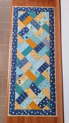 a blue and yellow patchwork quilt hanging on the wall next to a wooden frame