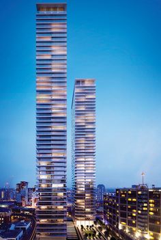 two tall buildings next to each other in front of a cityscape at night