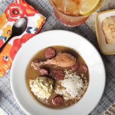 a white bowl filled with meat and rice next to a glass of orange juice on top of a table