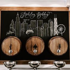 three wooden barrels sitting next to each other in front of a chalkboard with the words whiskey baby written on it