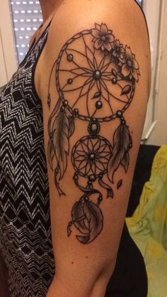 a woman's arm with a tattoo on it that has an image of a dream catcher