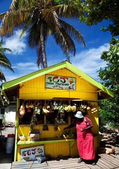 a woman standing in front of a yellow kiosk with bananas hanging from it