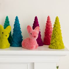 several different colored trees are sitting on a mantle