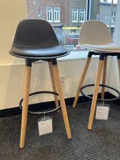 two black and white stools in front of a window with a sign on it