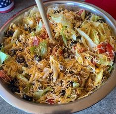 a silver bowl filled with shredded cheese and vegetables