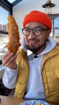 a man in an orange hat is holding up a large piece of food and smiling at the camera