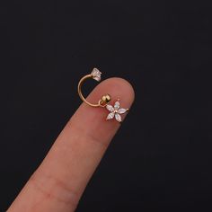 a person's finger with a gold ring and two small white flowers on it