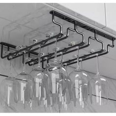 several wine glasses hanging from the ceiling in front of a rack with six wine glasses on it