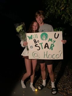 two girls holding up a sign that says will you be my star and hoco?