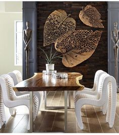 a dining room table with white chairs and an art piece on the wall behind it