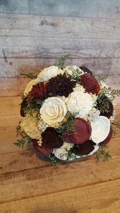 a bridal bouquet on a wooden table with white and red flowers in the center